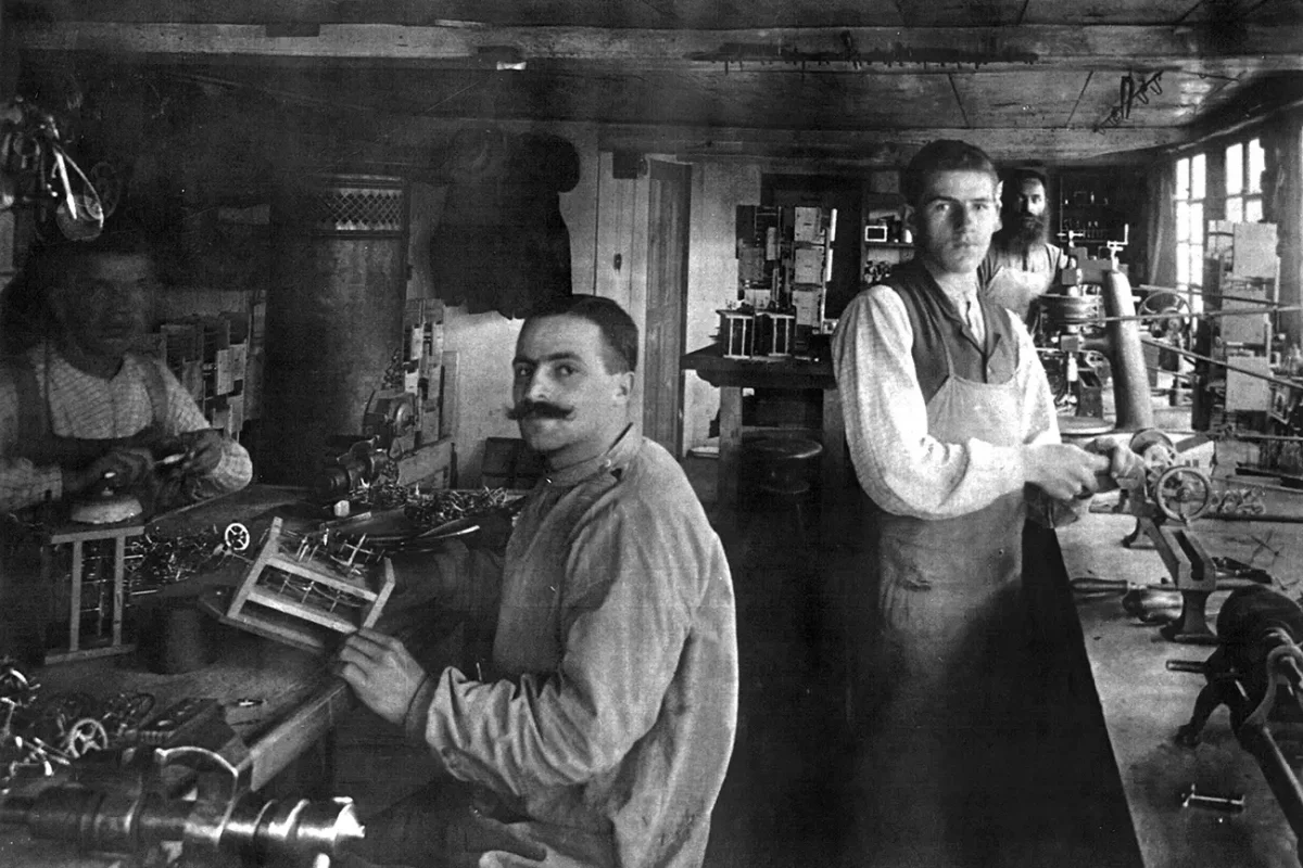 Arbeiter in einer historischen Werkstatt bei der Uhrwerkherstellung