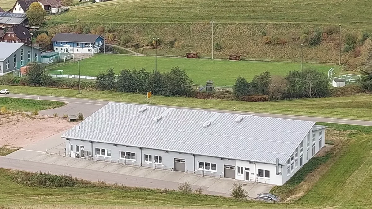 Industrielle Halle auf dem Land mit Fußballfeld im Hintergrund