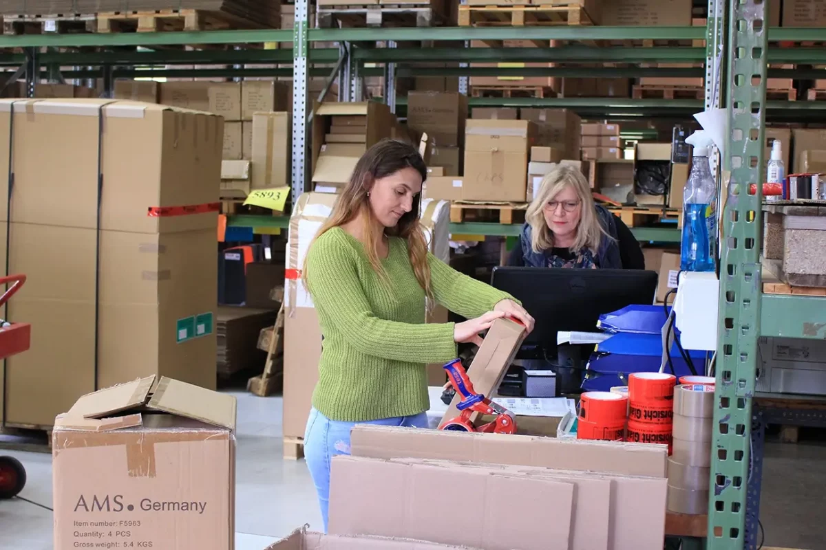 Frau verpackt Waren in Lagerhalle mit Kartons