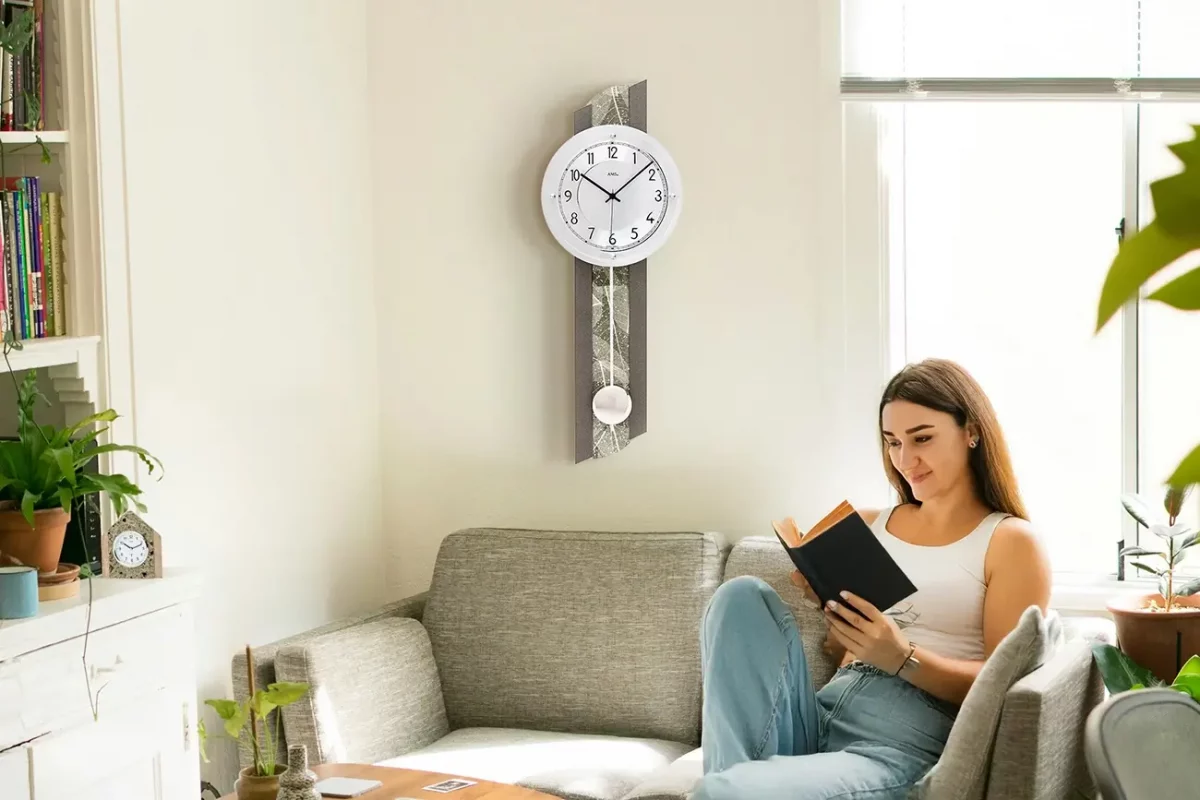 Frau liest auf Sofa neben moderner Pendeluhr