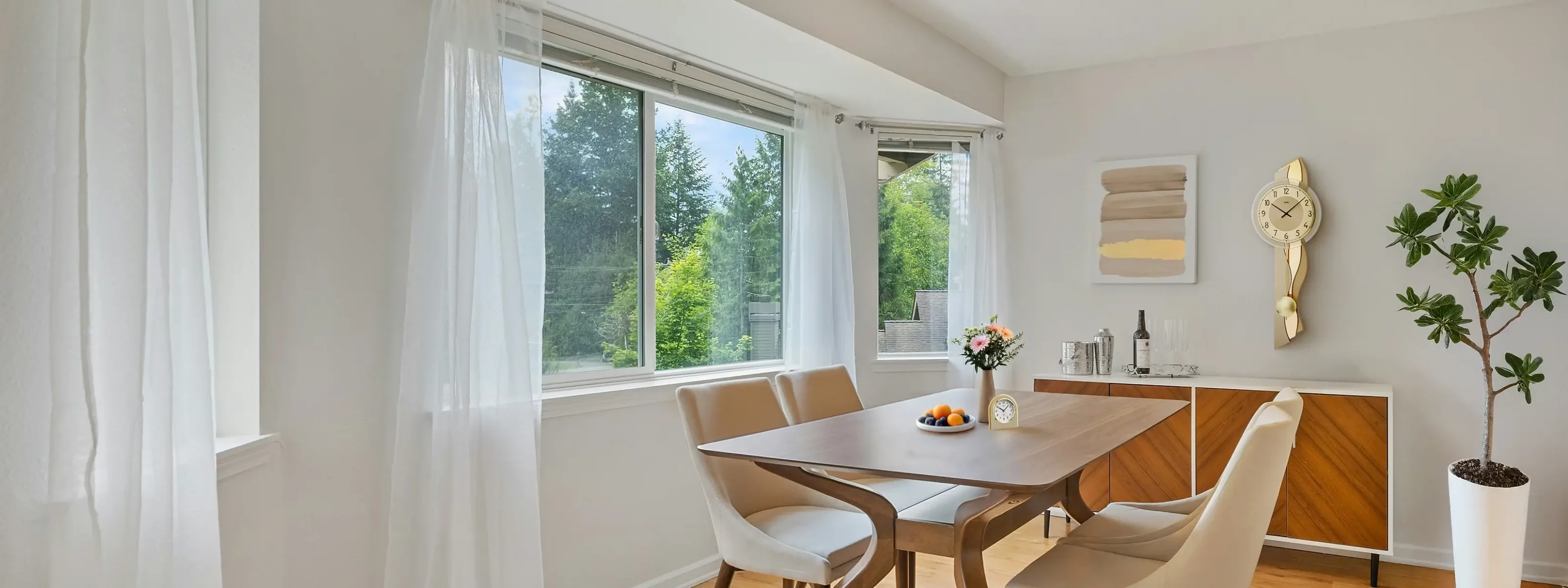 Helles Esszimmer mit Holztisch und großen Fenstern