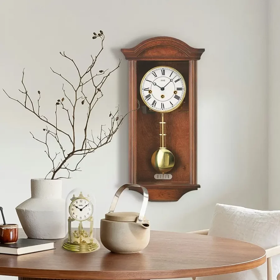 Klassische Pendeluhr an der Wand neben Tischarrangement mit Teekanne