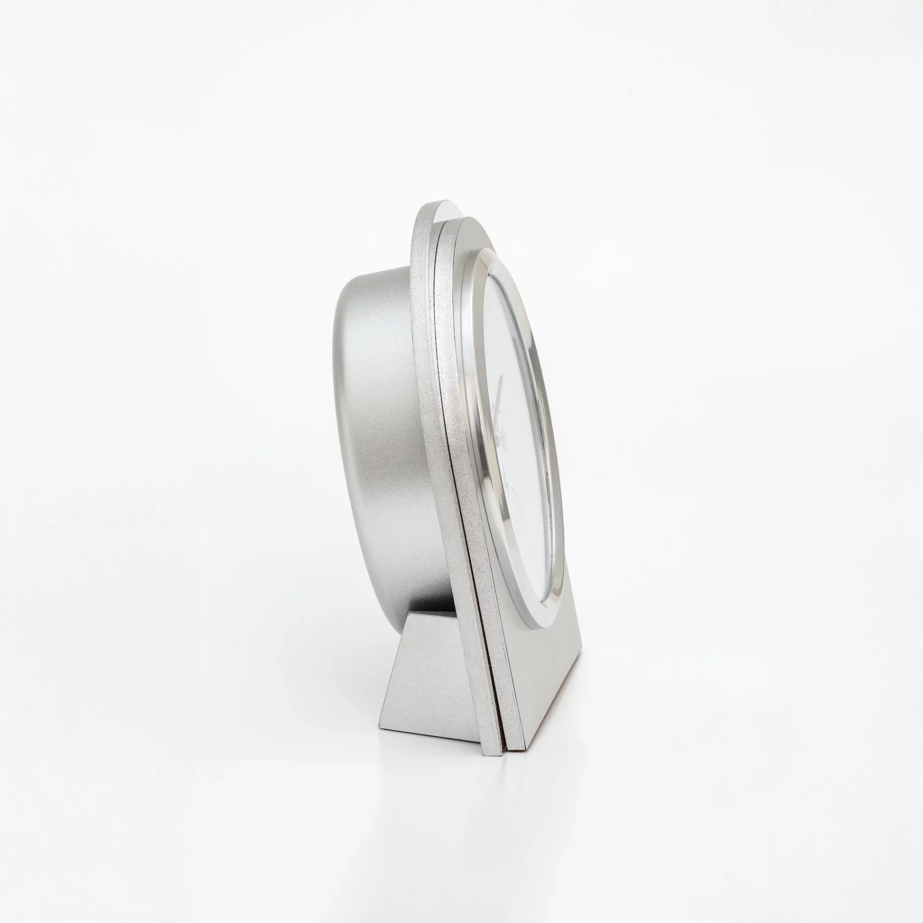 Silberne Tischuhr im seitlichen Profil vor weißem Hintergrund