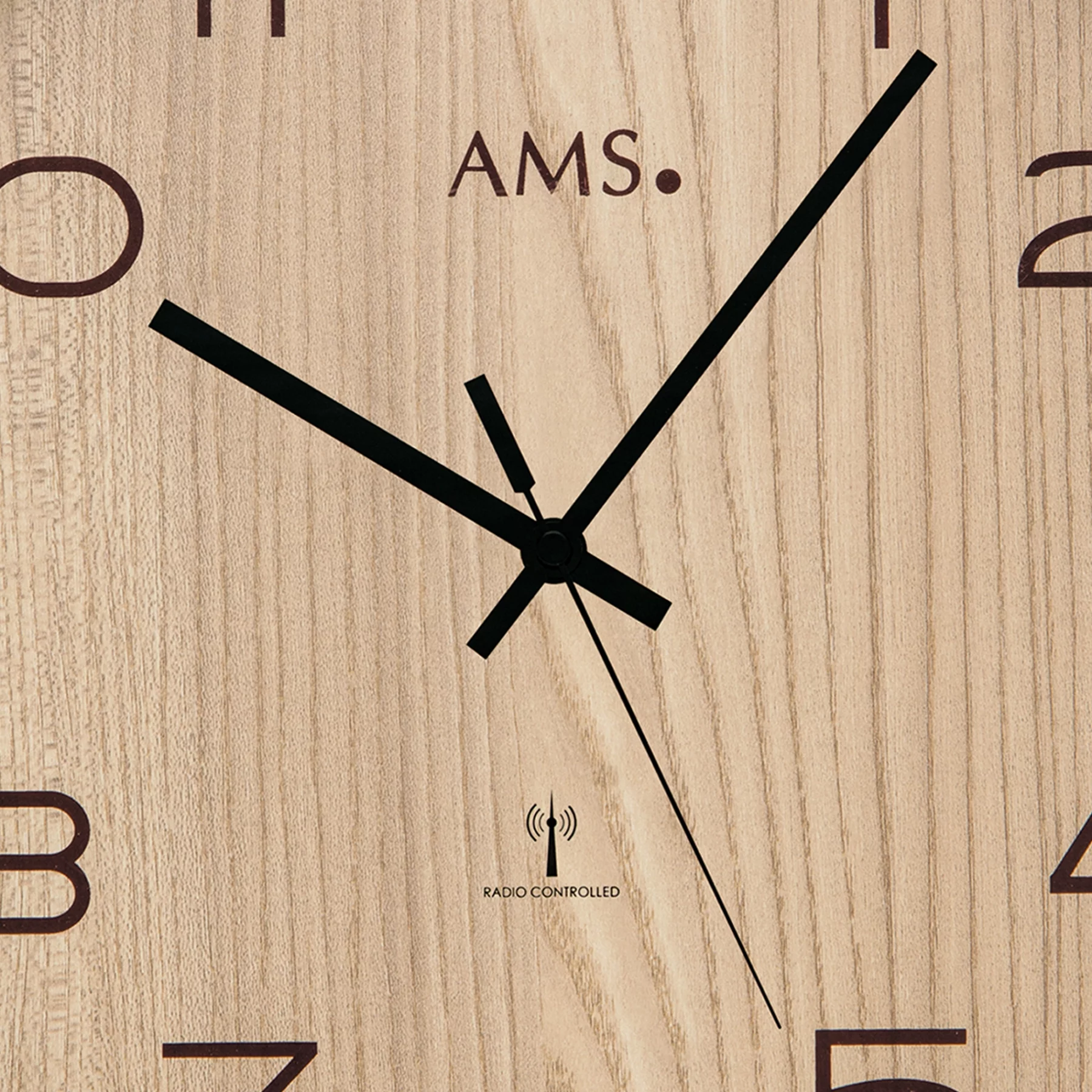 Holzwanduhr mit schwarzen Zeigern und AMS Logo