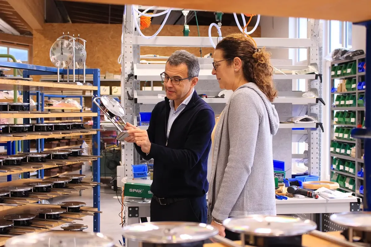 Zwei Personen in Werkstatt, betrachten Bleche