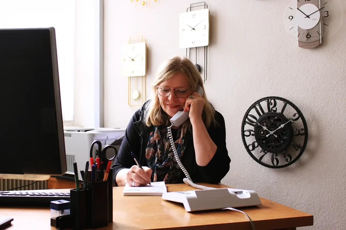 Frau telefoniert im Büro und macht Notizen