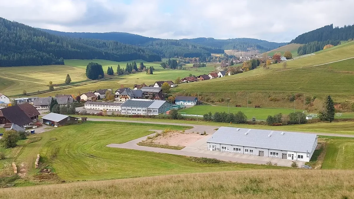 Malerisches Dorf im Schwarzwald mit grünen Hügeln und einer Produktionshalle