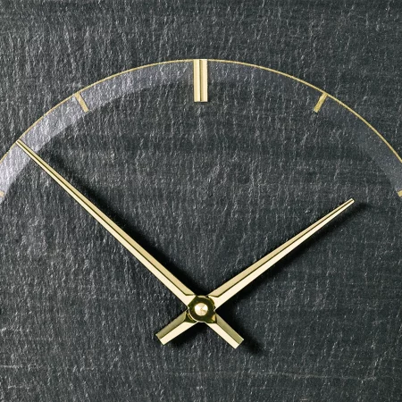 Goldene Uhrzeiger auf grauem Zifferblatt aus Schiefer
